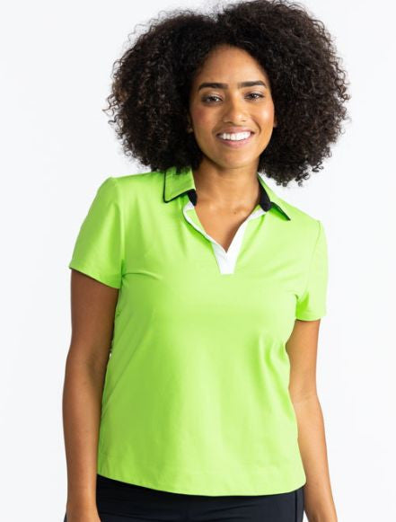 Front view of a smiling woman wearing the Classic and Fantastic Short Sleeve Golf Top in Grass Green. This is a solid grass green top with a V-neck front in white and is trimmed in black around the collar and has black on the interior of the collar.