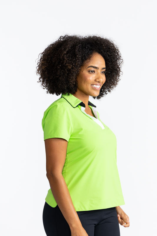 Right side view of the Classic and Fantastic Short Sleeve Golf Top in Grass Green. This is a solid grass green top with a V-neck front in white and is trimmed in black around the collar and has black on the interior of the collar.