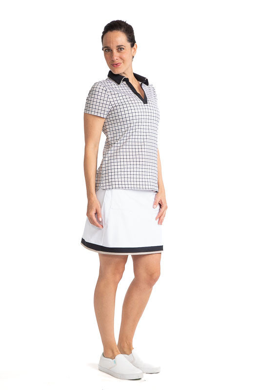 Full front and right side view of a woman golfer wearing the Classic and Fantastic Short Sleeve Golf Top in Quad Squad print and the Tee to Green Golf Skort in White.