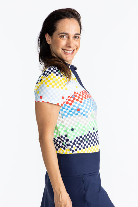 Right side view of a smiling woman wearing the Classic and Fantastic Short Sleeve Golf Top in Cheeky Check print. This print is made up of a checked horizontal patter that creates a horizontal wrap in black, grass green, lemon yellow, French blue, and tom
