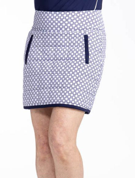 Front view of the Quilted and Cozy Golf Skort in Tees Please print. This is a navy blue and white printed skort with a navy blue band around the hemline and accents on the two front zippered pockets. There is also a back welt pocket on the waistband that 