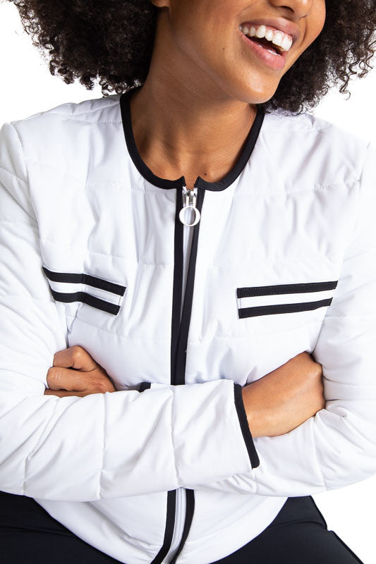 Tight front view of a woman wearing the Polished for Play Golf Jacket in White. This jacket has black accents around the neckline and on each size of the front zipper, two decorative stripes, creating faux breast pockets on each side, two stripes on each 