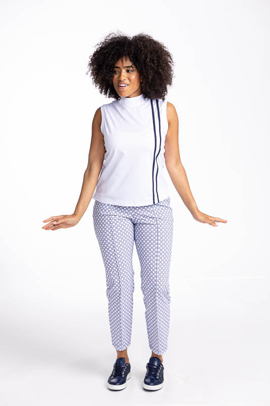 Full front view of a smiling woman wearing the No Break Sleeveless Golf Top in White and the Tailored Crop Golf Pants in Tees Please print. This is a white top with two vertical navy blue stripes from the left shoulder to the hem. This top also features a