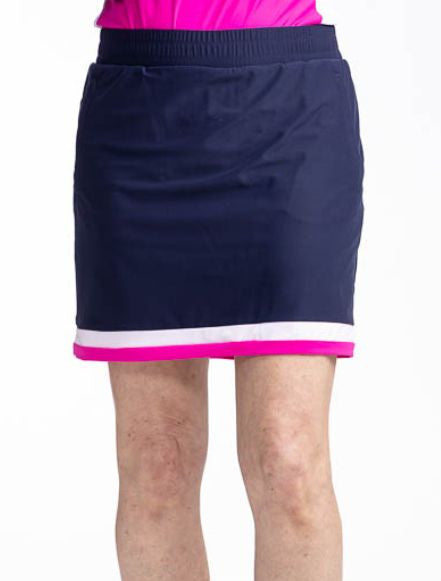 Front view of the Comfy and Cozy Golf Skort in Navy Blue. This is a navy blue skort with two horizontal stripes around the hemline - one white and one open air pink. It also features two side zippered pockets with a built-in tee holder, two back zippered 