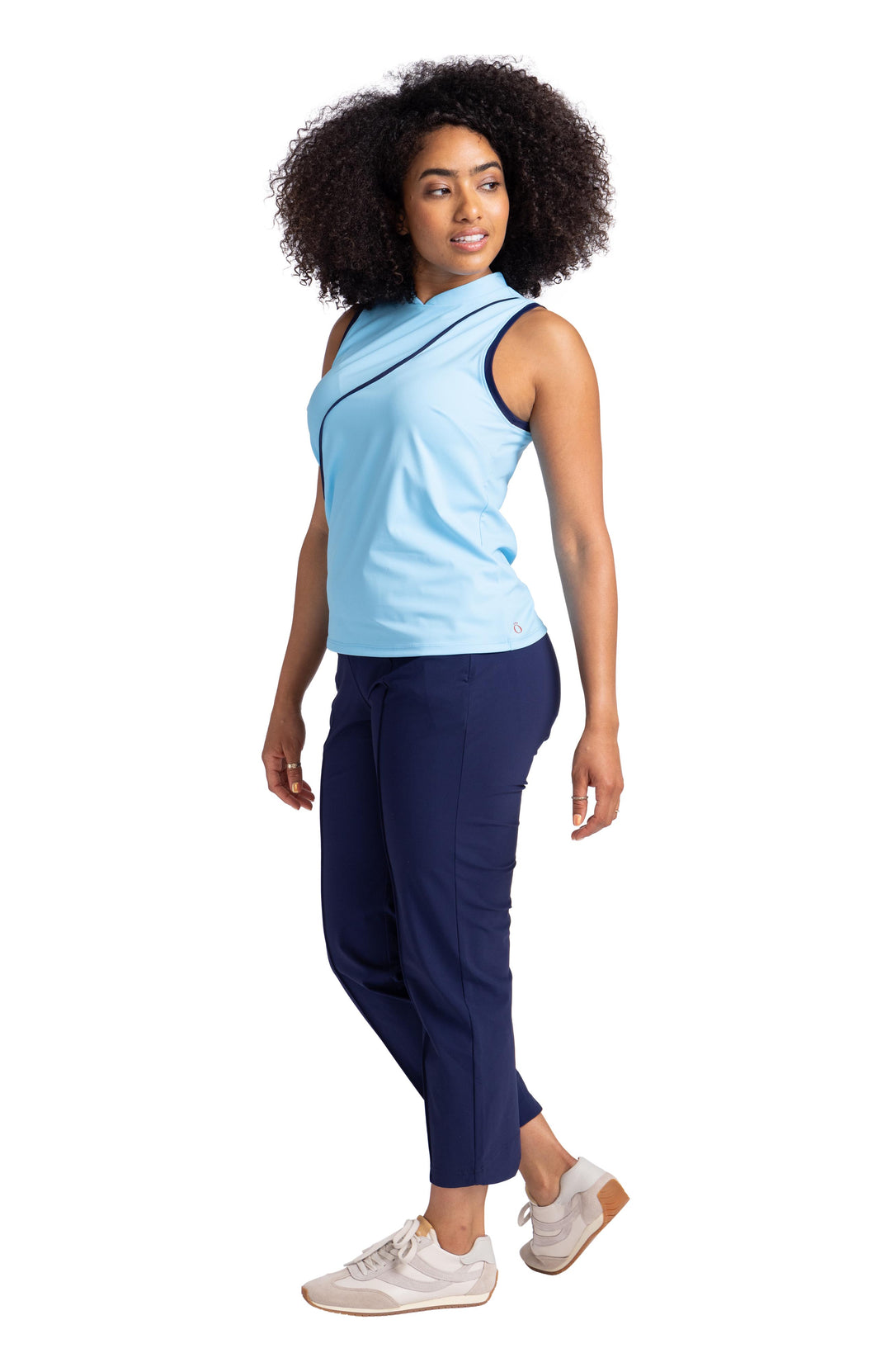 Full side view of a woman wearing a light blue sleeveless top with navy blue contrasting trim on the armholes and a navy blue wavy seam down the front. The top is paired with the navy blue Tailored Crop Golf Pant. 