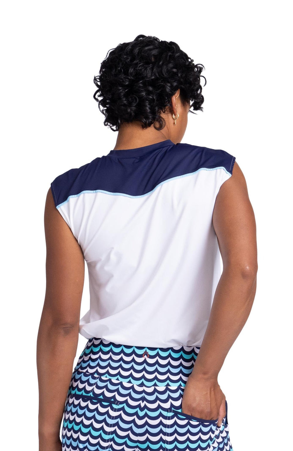 Back view of a woman wearing a cap sleeved top with a navy blue panel above the wavy yoke seam and white below the yoke. 