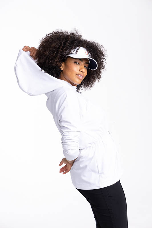 Right side view of a woman wearing the Aprés 18 Anorak Long Sleeve Hoodie in white and the No Hat Hair Visor in White. In this view, you can also see the full length of the hoodie on this top.