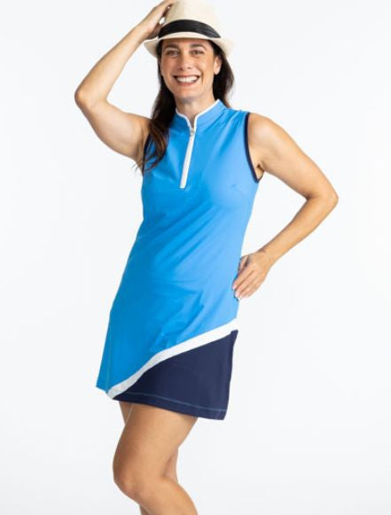 Front view of a smiling woman wearing the Tend The Flag Sleeveless Golf Dress in French Blue. This dress has a white quarter zip on the front of the dress, navy blue accents around each arm hole, a diagonal white stripe on the lower left quarter of the fr