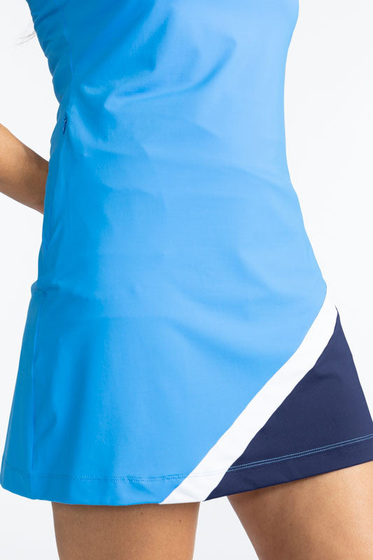 Close front view of the lower portion of the Tend The Flag Sleeveless Golf Dress in French Blue. This dress has a white quarter zip on the front of the dress, navy blue accents around each arm hole, a diagonal white stripe on the lower left quarter of the