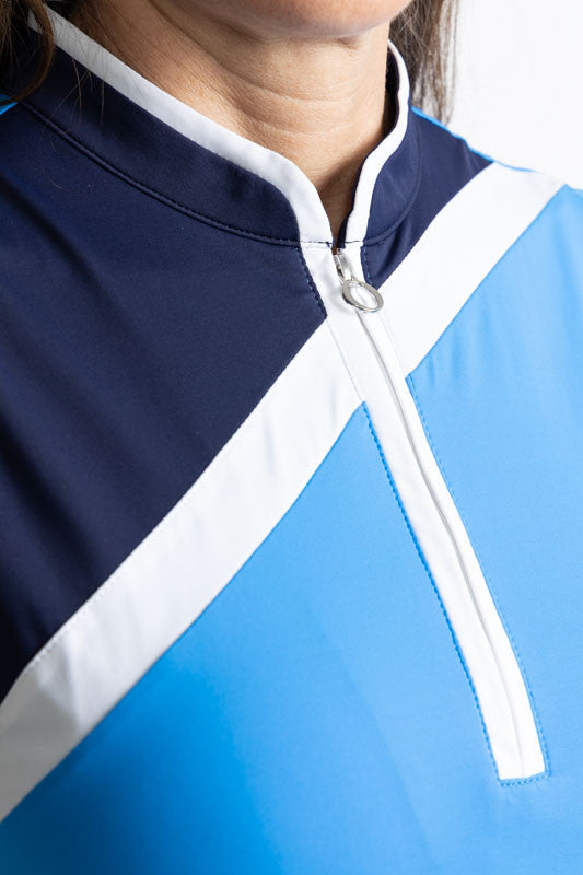 Close front view of the Tend The Flag Sleeveless Golf Top in French Blue. This top consists of a French blue background with a white diagonal stripe and a navy blue triangular section from the top of the left shoulder down to just below the bustline on th