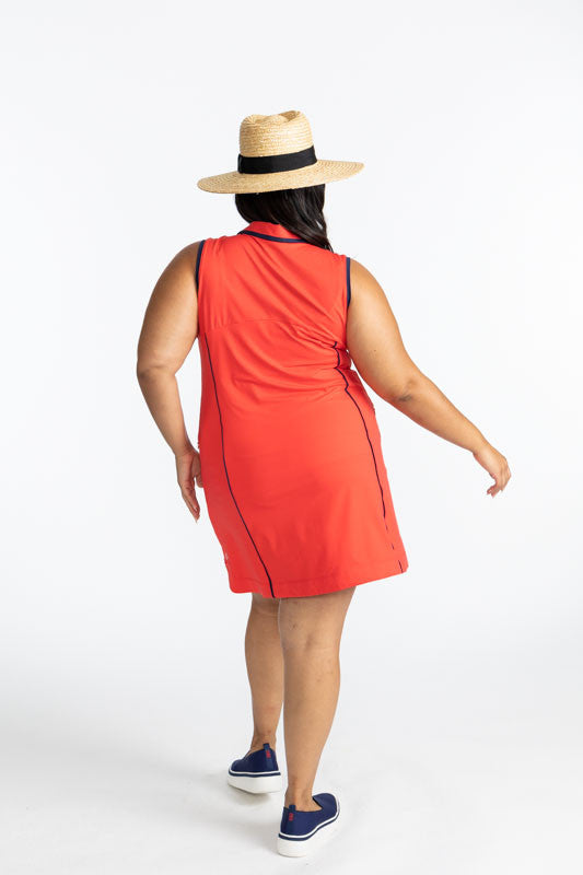 Back view of the In The Cup Sleeveless Golf Dress in Tomato Red. This dress has black accents around the collar and down the front quarter zip, around each armhole, and one black line down each side on the front of this dress. 