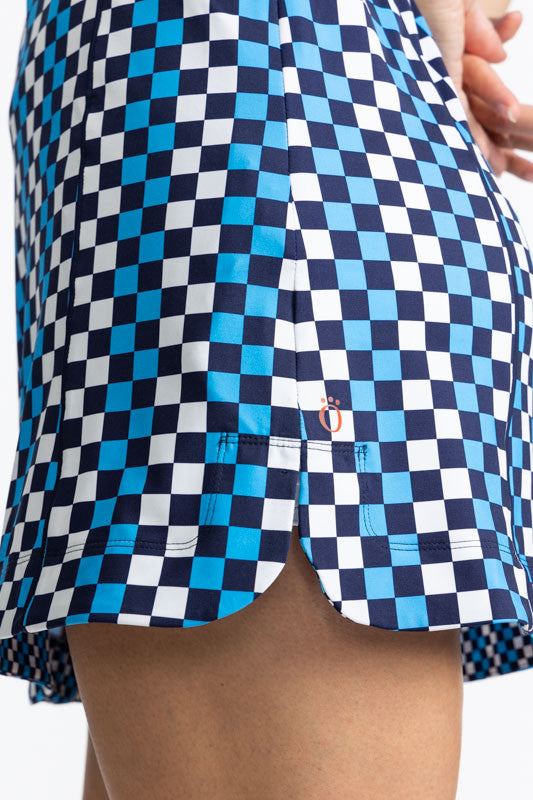 Left side hemline view of the In The Cup Sleeveless Golf Dress in Check It Out. The check it out print consists of French blue, black, and white in a checker board print. There are also navy blue accents around the neckline, front quarter zip, and around 