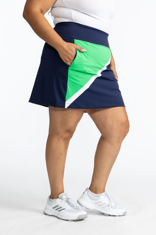 Right side of the Tend the Flag Golf Skort in Navy Blue. This skort has a White diagonal stripe and a Kelly Green triangle on the right side of this skort. 