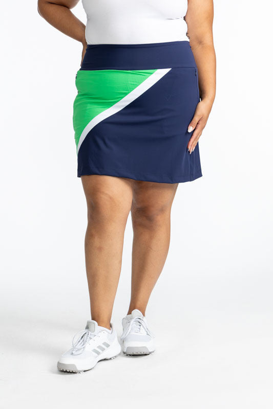 Front view of the  Tend the Flag Golf Skort in Navy Blue. This skort has a White diagonal stripe and a Kelly Green triangle on the right side of this skort. 