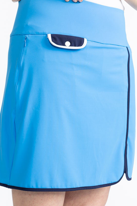 Close front view of the Club Champion Golf Skort in French Blue. This skort is solid French Blue with black trim around the bottom and up the split on the front of the skort. There is also a front flap pocket in black with white trim and a white snap. In 