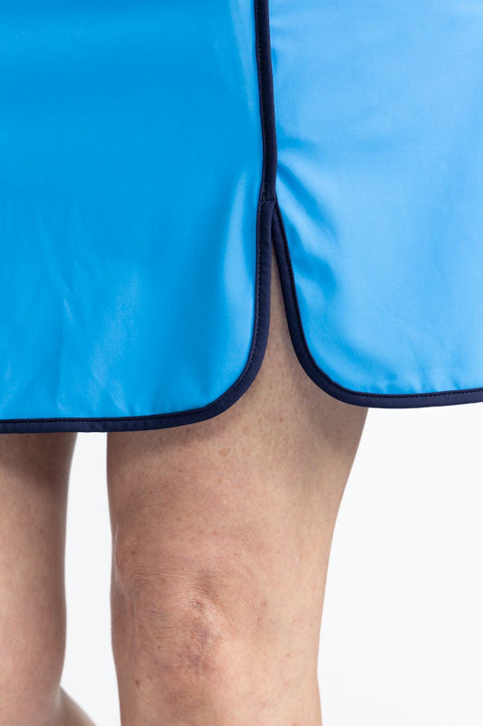 Close front and left side view of the hemline and the front split on the Club Champion Golf Skort in French Blue. This skort is solid French Blue with black trim around the bottom and up the split on the front of the skort. There is also a front flap pock