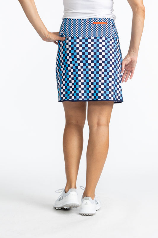 Back view of the Club Champion Golf Skort in Check It Out print. This print is a mix of French blue, black, and white checks on this skort with navy blue trim around the bottom and up the split on the skort. There is a front flap pocket with black trim ar