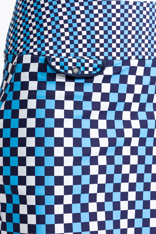 Close front right view of the front flap pocket on the Club Champion Golf Skort in Check It Out print. This print is a mix of French blue, black, and white checks on this skort with navy blue trim around the bottom and up the split on the skort. 