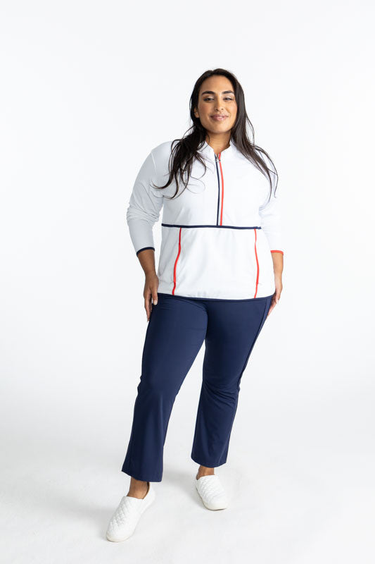 Smiling woman wearing the Apres 18 Half Zip Pullover in White and the Smooth Your Waist Crop Pants in Navy Blue
