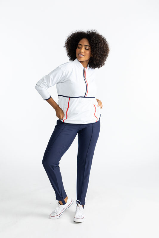 Smiling woman wearing the Apres 18 Half Zip Pullover in White and the Ankle Warmer Stirrup Pants in Navy Blue