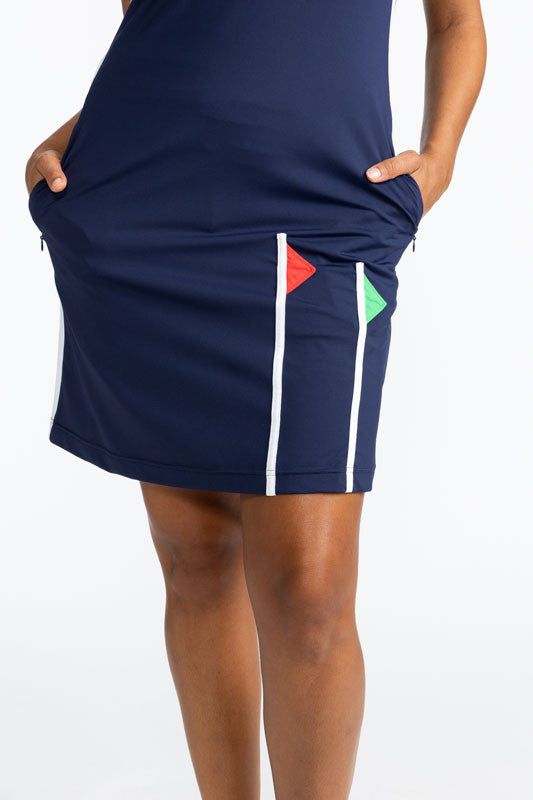 Front view of the lower half of the Flagstick Sleeveless Golf Dress in Navy Blue. This dress has a navy blue background, tomato red around each arm hole, one white stripe that runs the full length of the dress on each side, and two golf flagsticks on the 