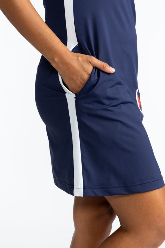 Right side view of the Flagstick Sleeveless Golf Dress in Navy Blue. This dress has a navy blue background, tomato red around each arm hole, one white stripe that runs the full length of the dress on each side, and two golf flagsticks on the front of the 