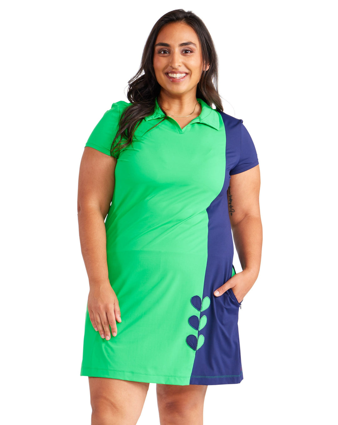 Front view of woman in a green and blue short sleeve, with polo collar dress.  Side zippered pockets with vertical heart detail at the bottom