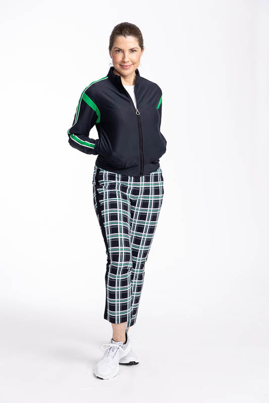 Full front view of a woman wearing the Smooth Your Waist Crop Golf Pants in Tartan Plaid and the Warm Up Jacket in black.
