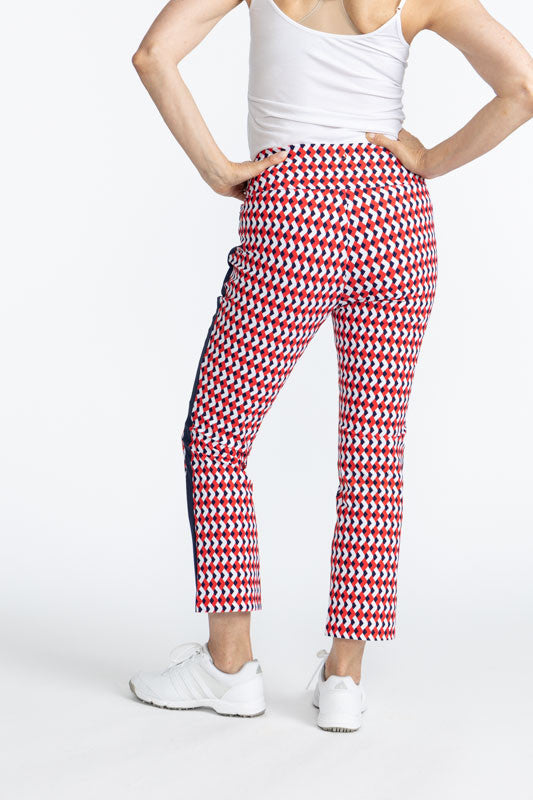 Back view of the Smooth Your Waist Crop Pants in Chevron Tomato Red. The Chevron Tomato Red print is comprised of red, white, and blue chevrons in a repeating pattern on the pants with a navy blue stripe that runs down each side. 