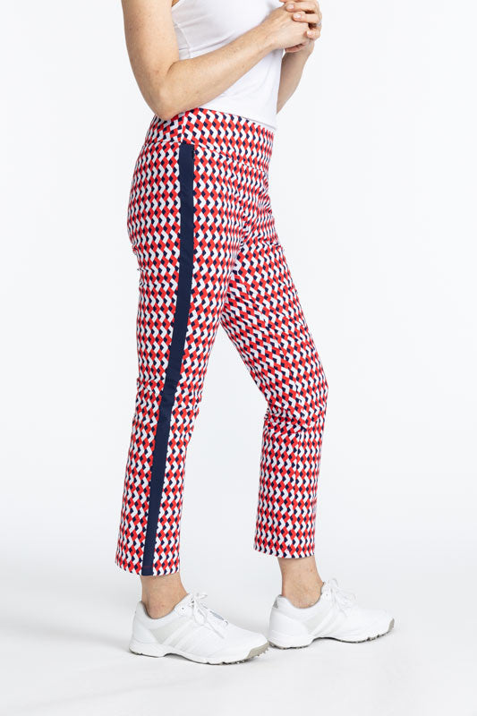 Right side view of the Smooth Your Waist Crop Pants in Chevron Tomato Red. The Chevron Tomato Red print is comprised of red, white, and blue chevrons in a repeating pattern on the pants with a navy blue stripe that runs down each side. 