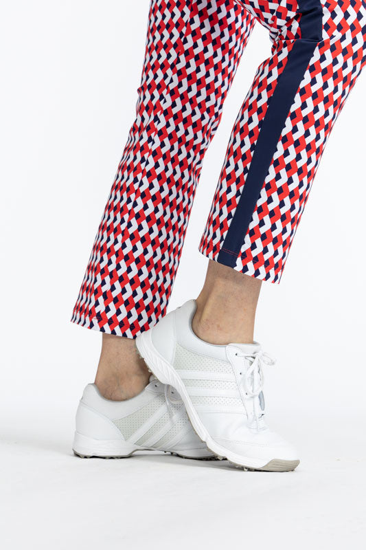 Close right side view of the hemline on the Smooth Your Waist Crop Pants in Chevron Tomato Red. The Chevron Tomato Red print is comprised of red, white, and blue chevrons in a repeating pattern on the pants with a navy blue stripe that runs down each side