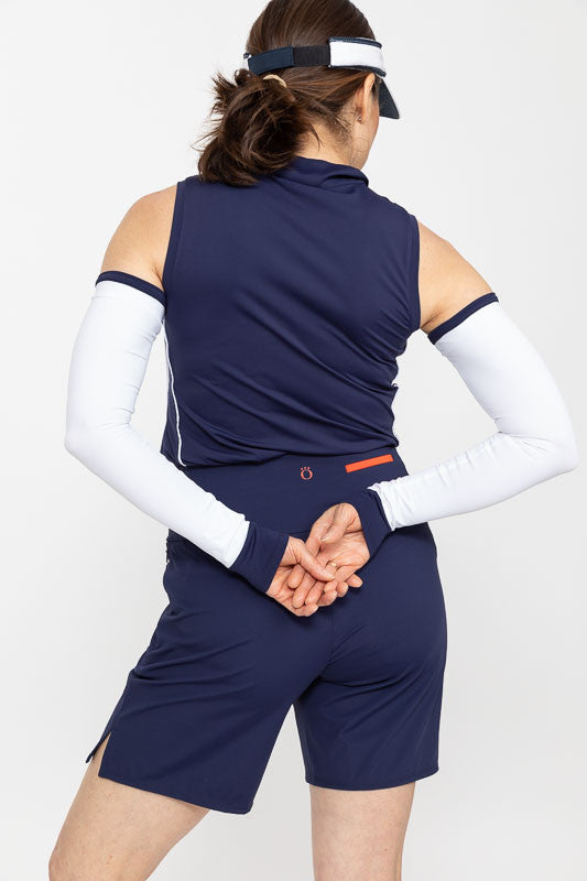Back view of a woman golfer wearing a pair of Sun's Out Golf Sleeves in navy blue