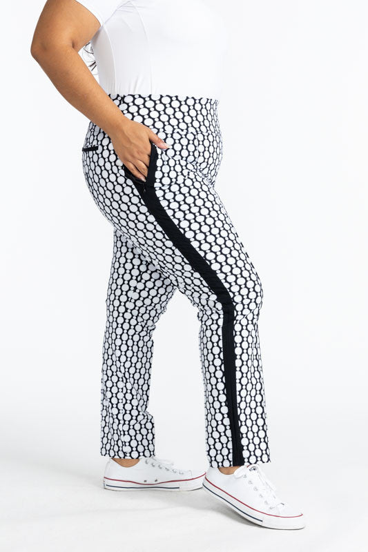 Full right side view of the Tailored Track Golf Pants in Spiral Floral. This print is a retro-inspired abstract black and white flower pattern. There is one black stripe that runs the length on each side of these pants.
