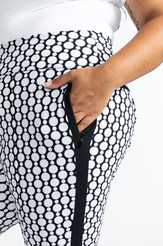 Close left side view showing the one of the pockets on the Tailored Track Golf Pants in Spiral Floral. This print is a retro-inspired abstract black and white flower pattern. There is one black stripe that runs the length on each side of these pants.