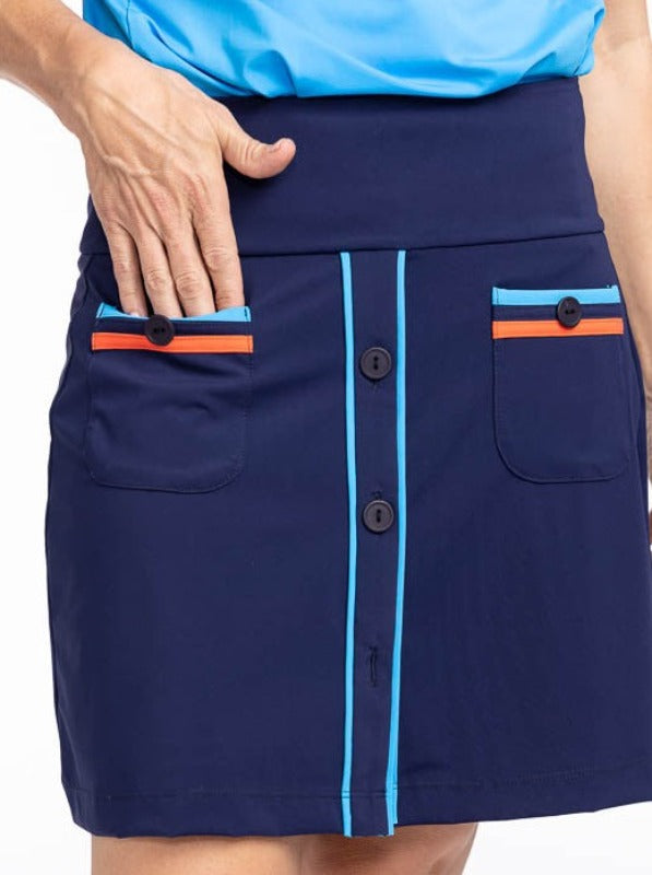 Front view of the Long Strides Golf Skort in Navy Blue. This skort is a solid navy blue with two patch pockets that have a pacific blue stripe above the button and an orange stripe below the button on each pocket. The front also has three navy blue button