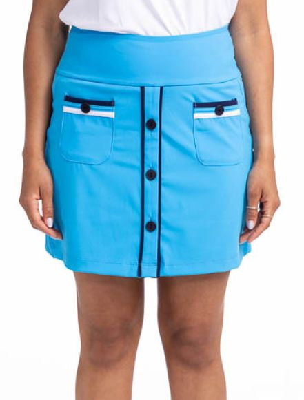 Front view of the Long Strides Golf Skort in Pacific Blue. This skort is a solid blue with two patch pockets that have a navy blue stripe above the button and a white stripe below the button on each pocket. The front also has three navy blue buttons and n