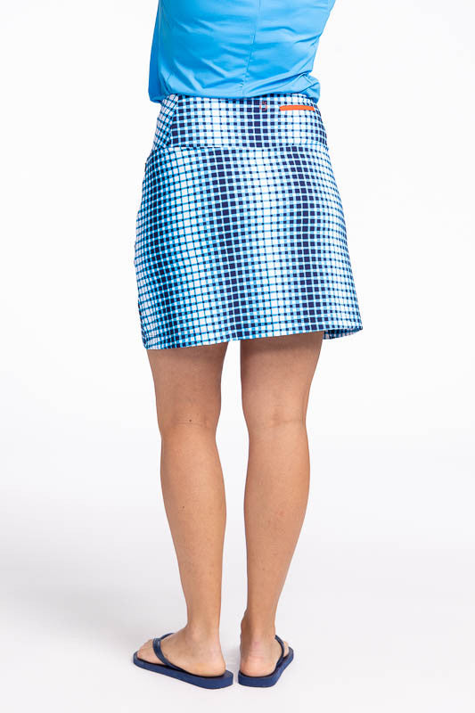 Back view of the Summer Sass Golf Skort in Ocean Plaid. This print is a vertical repeating gradient of white to blue checkered print. This skort has a 3/4 zipper on the front left side, two zippered pockets with a built-in tee holder, and a built-in, brea