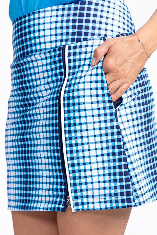 Close left side view of one of the pockets on the Summer Sass Golf Skort in Ocean Plaid. This print is a vertical repeating gradient of white to blue checkered print. This skort has a 3/4 zipper on the front left side, two zippered pockets with a built-in