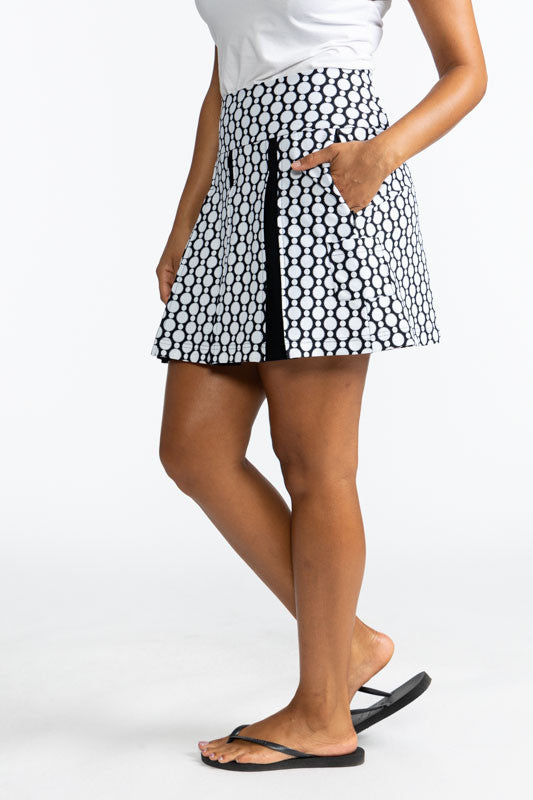 Full left side view of the Swing and Swirl Golf Skort in Spiral Floral print. This print is a retro style black and white floral pattern. This skort has three black panels tucked in between the front panels of this skort.