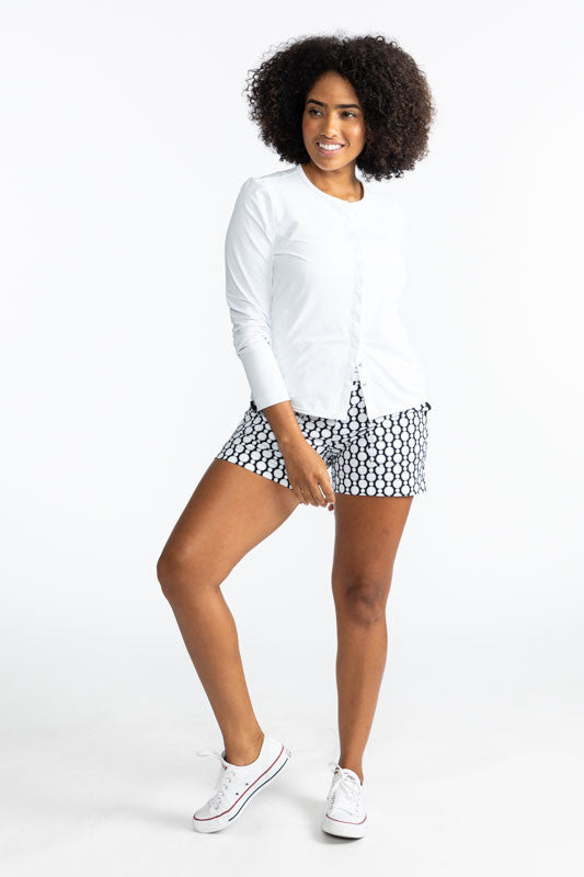 Full front view of a smiling woman wearing the Party Cardi in White and the Carry My Cargo Golf Shorts in Spiral Floral print