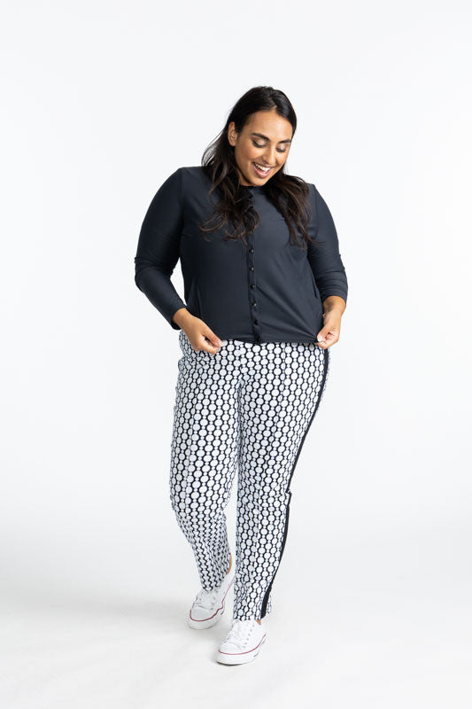 Full front view of a smiling woman wearing the Party Cardi in Black and the Tailored Track Golf Pants in Spiral Floral print