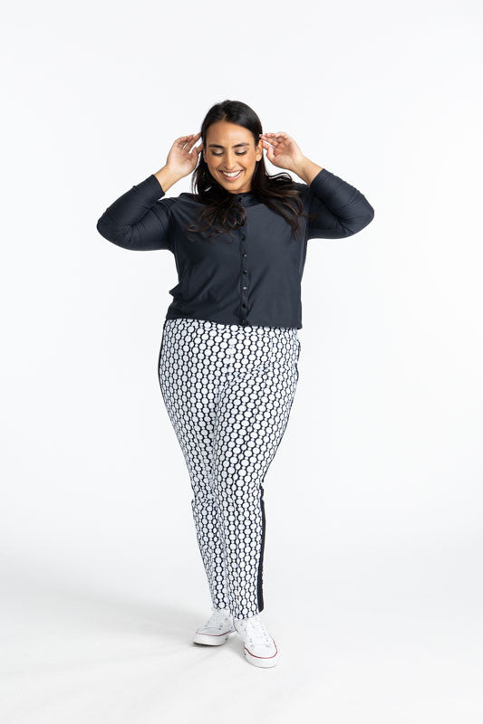 Full front view of a smiling woman wearing the Party Cardi in Black and the Tailored Track Golf Pants in Spiral Floral print