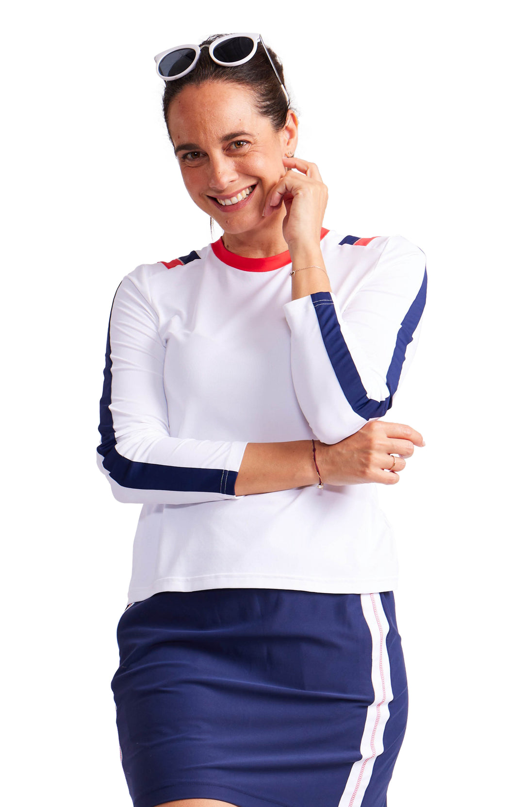 Full front view of a woman wearing a longsleeve white top with a navy blue stripe down each sleeve, red and navy blue vertical stripes on each shoulder and red crew neck collar.