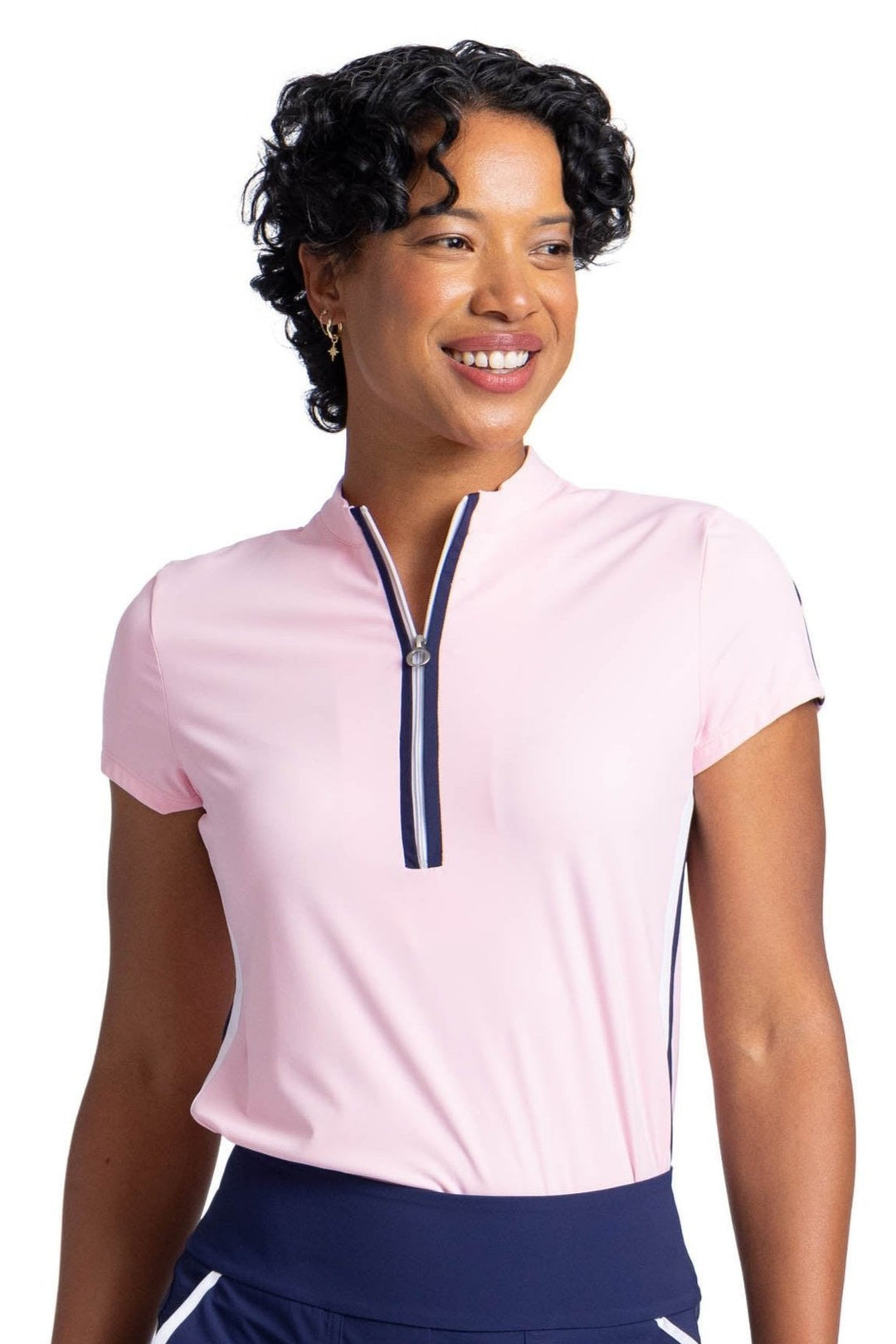 Woman wearing a soft pink, short sleeve top. The top has a mock neck with a three-quarter white zipper. The zipper has navy blue binding on both sides. 