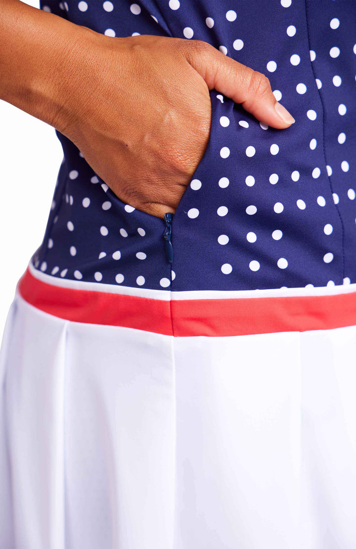 Close, detailed view of a woman putting her hand in the side pocket of the domino navy dress. 